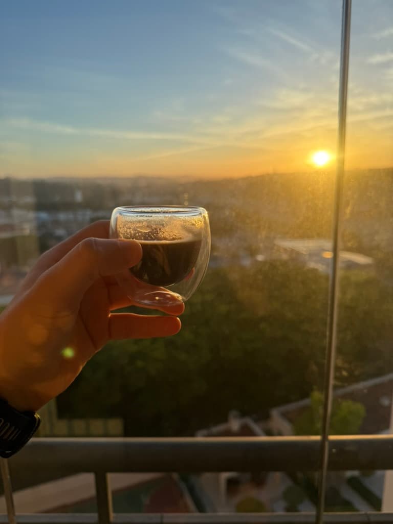 An espresso held up against the sunrise