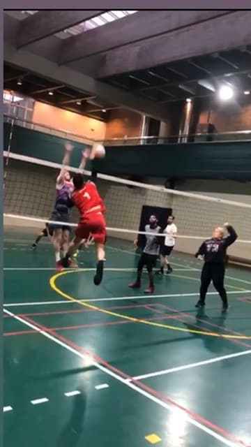 Marcos jumping to attack in an indoor volleyball game