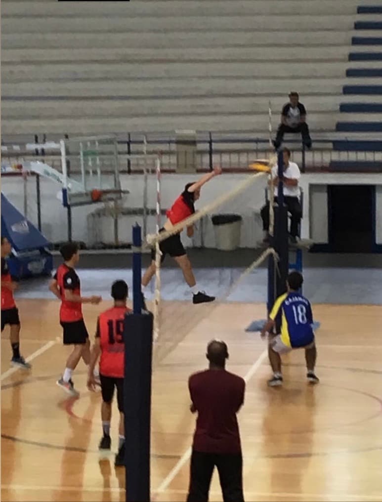 Marcos spiking over the net in a volleyball match